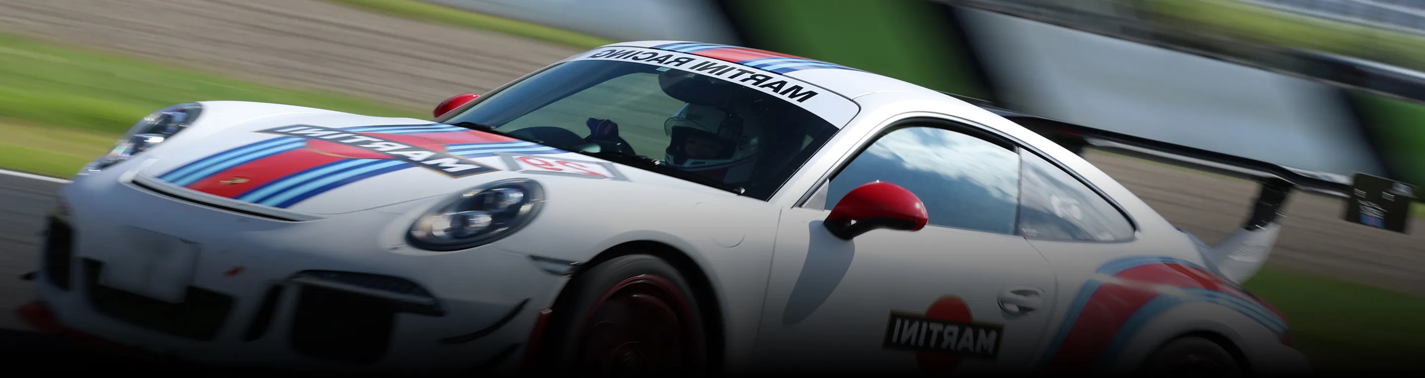 サーキットを高速走行するマルティーニカラーのポルシェ911 GT3