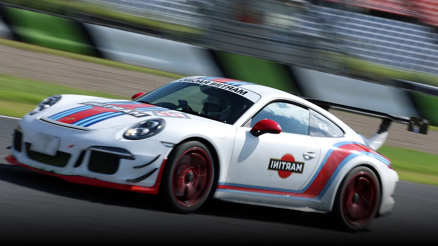 サーキットを高速走行するマルティーニカラーのポルシェ911 GT3
