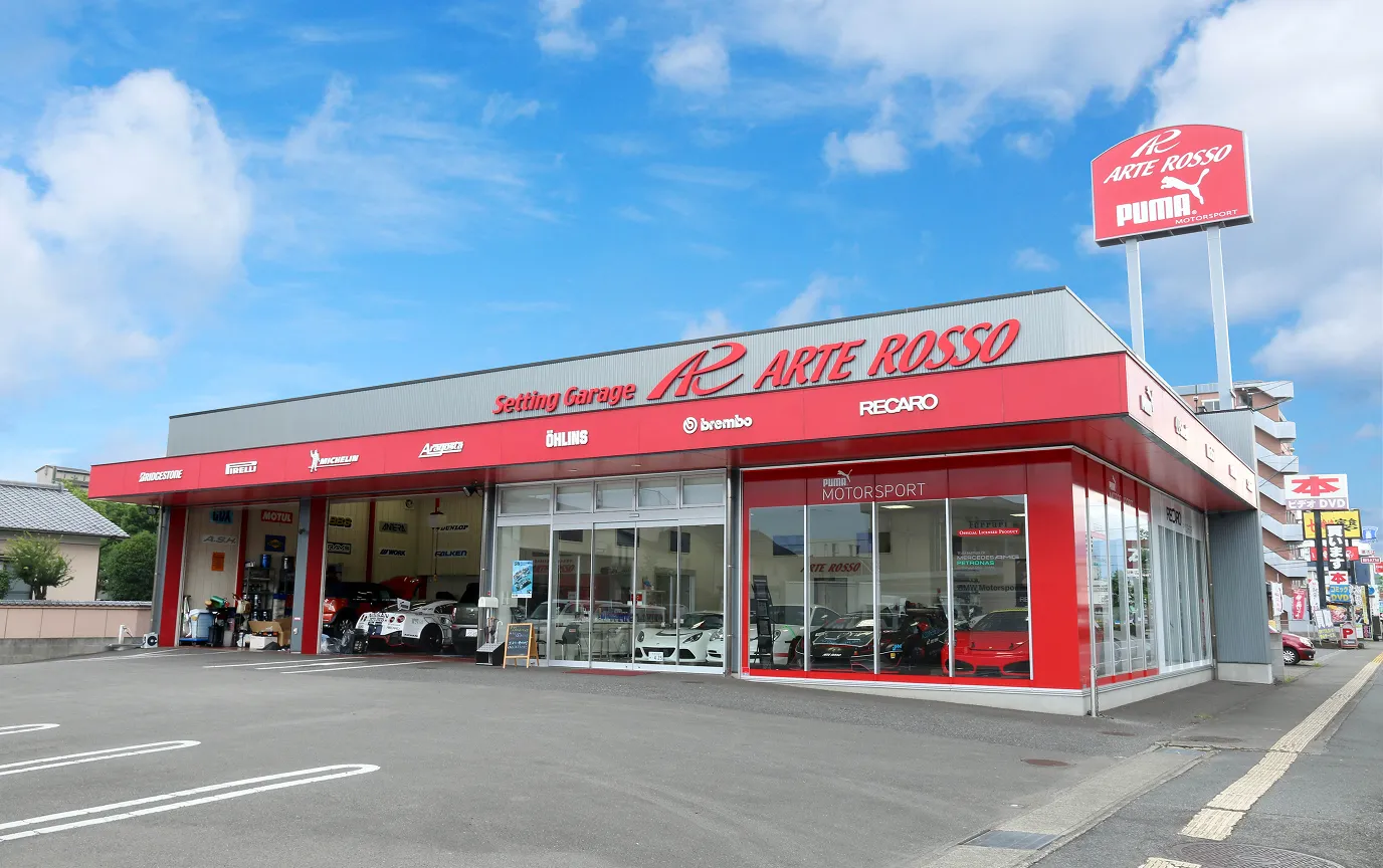 ARTE ROSSOのモダンな店舗外観。BREMBO, PUMAなどのロゴが目立つ、チューニングカー専門ガレージ